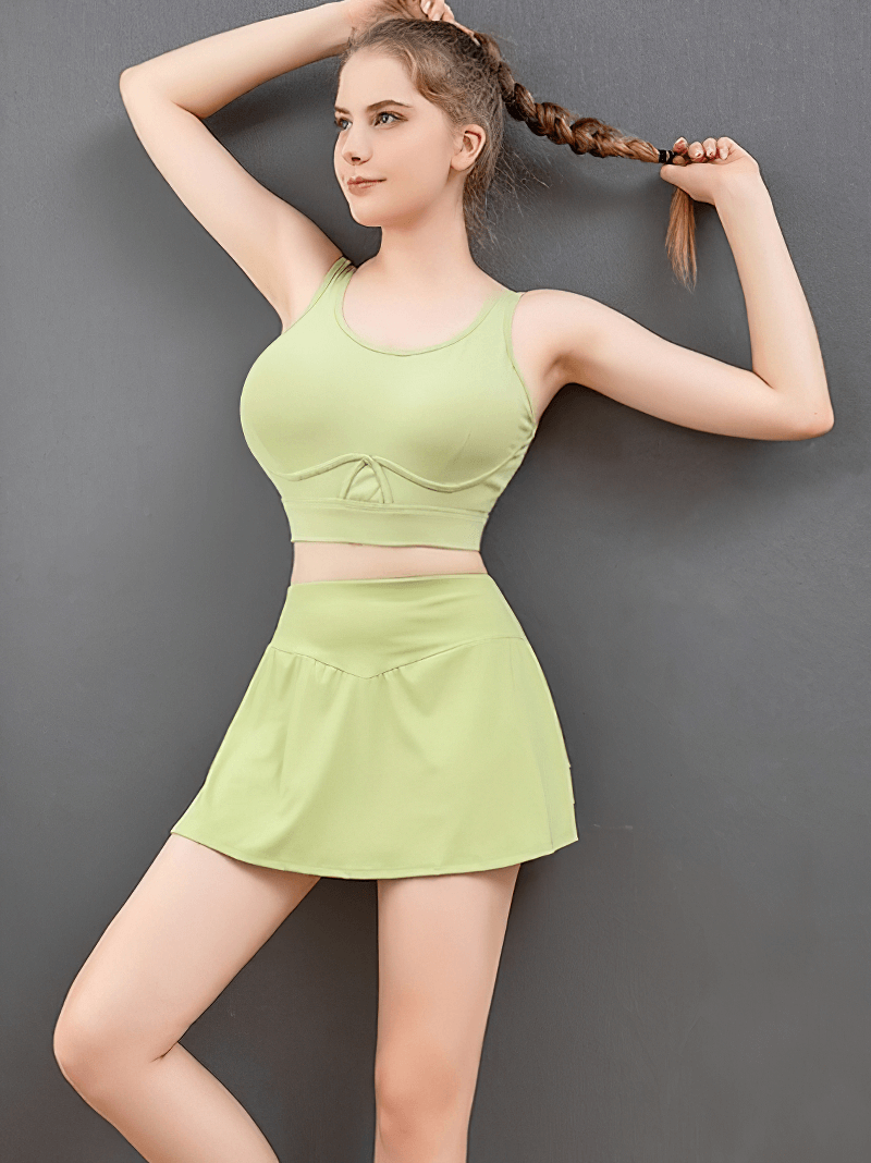 Woman in green pleated shorts-skirt and tank top, showcasing flexible, moisture-wicking activewear for golf and tennis.